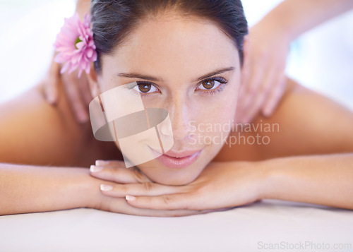 Image of Relax, massage and portrait of woman at spa with smile, flower for health with luxury holistic treatment. Self care, peace and girl on table with masseuse for body therapy, wellness and hotel service