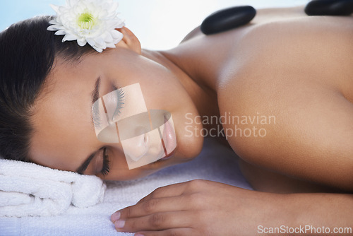 Image of Sleeping, hot stone or woman with flower in spa for wellness, treatment or hospitality. Relax, resort or salon with female person, client or masseuse in hotel on holiday vacation for beauty therapy