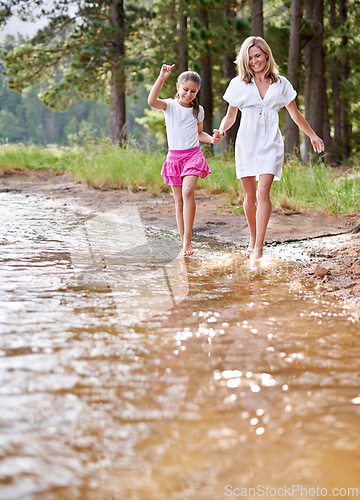 Image of Mother, daughter and happiness outdoor in river for bonding, support or holding hands on holiday in nature. Family, woman and girl child with smile or adventure on vacation, travel and lake with love