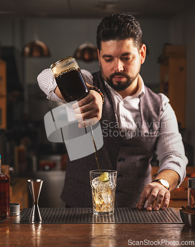 Image of Bartender pouring craft cocktail at bar