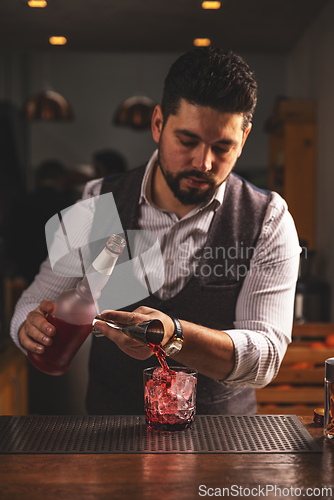 Image of Expert bartender pouring cocktail at bar