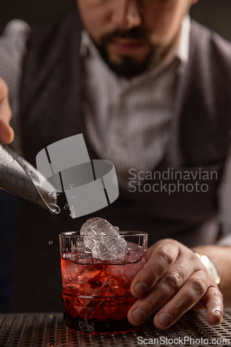 Image of Bartender pouring cocktail at bar