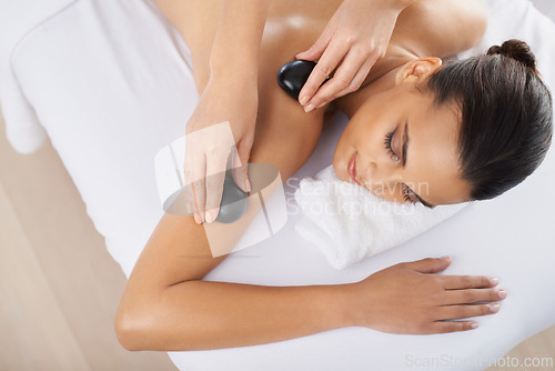 Image of Hot stone, woman and hands massage in top view for skincare, beauty and pamper shoulder for wellness at salon. Therapist, rocks and person at spa for treatment, body and relax with masseuse above