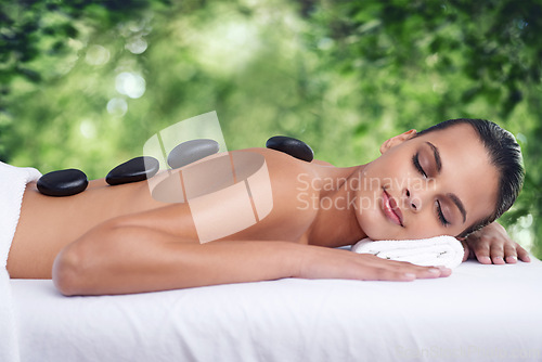 Image of Hot stone, massage and woman outdoor to relax, beauty and pamper back for wellness at luxury salon. Therapy, rocks and person in nature for skincare treatment, peace or calm for body health at spa