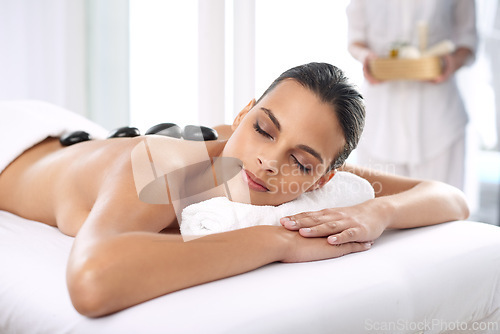 Image of Nap, hot stone and woman with massage at spa for wellness, health and back treatment. Self care, cosmetic and young female person sleeping for warm rock skin therapy at natural beauty salon.