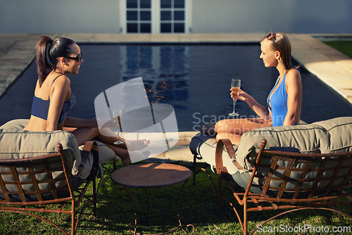 Image of Women, friends and relax with wine by pool for holiday, vacation or summer adventure with sunglasses and smile. People, swimwear and happy with champagne in backyard or garden of hotel accommodation