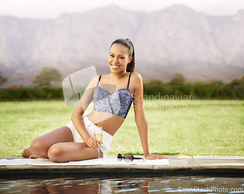 Image of Happy woman, portrait and champagne by pool in relax for swimming, holiday or outdoor weekend in nature. Attractive or young female person sitting by the water in summer fashion with glass or drink