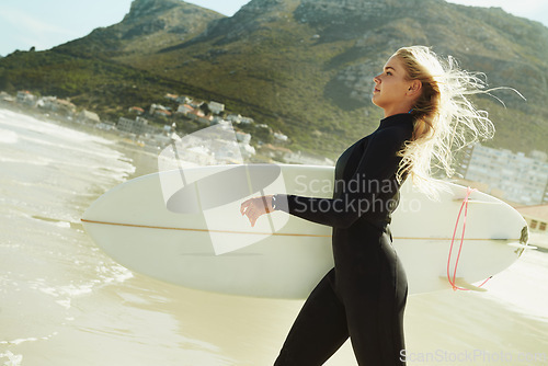 Image of Profile, beach in summer and woman walking with surfboard for sports, fitness or exercise outdoor on sand. Earth, sky and water with confident young surfer in wetsuit for travel, vacation or holiday