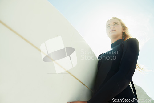 Image of Face, flare and woman on beach with surfboard from below for travel, vacation or adventure on coast in summer. Nature, fitness or exercise with confident young surfer person in wetsuit for recreation