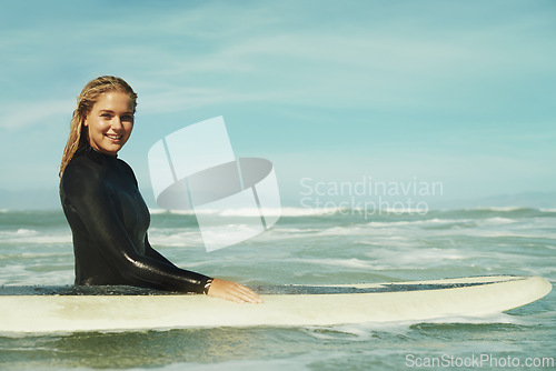 Image of Portrait, smile and woman with surfboard in ocean for sports, vacation or holiday in summer. Sky, sea and waves with happy young surfer person in wetsuit for travel, fitness or exercise in nature