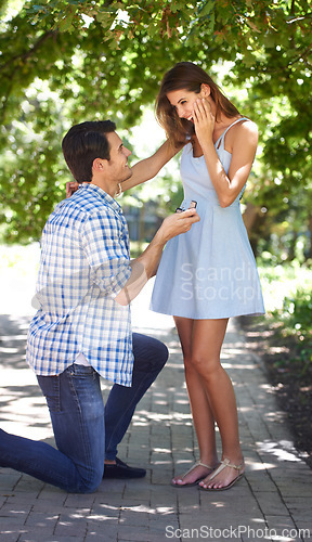 Image of Man, woman and kneeling or proposal with engagement ring in park for question, happiness or jewellery. Couple, love and commitment or save the date in nature or wedding announcement, summer or garden