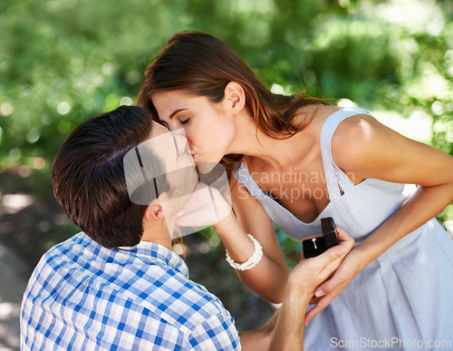 Image of Man, woman and kiss for engagement proposal with ring for outdoor question for yes, save the date or commitment. Couple, love and kneeling with jewellery in park for wedding event, promise or garden