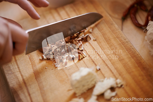 Image of Knife, person chop nuts and cooking, salad and healthy food for diet, nutrition and wellness at home. Meal prep in kitchen, wood board and prepare dish for lunch or dinner with closeup of ingredients