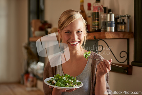 Image of Portrait, happy woman and eating salad in kitchen at home, nutrition and leafy greens for healthy diet. Vegetables, bowl and face of hungry person with food, fork and organic vegan meal for wellness