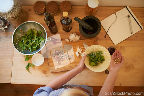 Image of Cooking, person hands and salad in a home with diet, nutrition and healthy food from above. Kitchen, bowl and leaves for organic and vegan lunch with nuts and wood board in a house with wellness