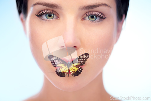 Image of Portrait, beauty and butterfly with natural woman in studio on blue background for skincare or wellness. Spa, face or lips and confident young model looking confident with skin treatment routine