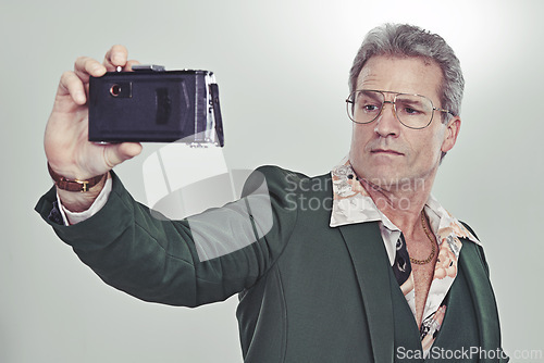 Image of Mature man, fashion and selfie with camera in photography, memory or cool style on a gray studio background. Senior, male person with glasses and posing for photo, picture or trend in formal clothing