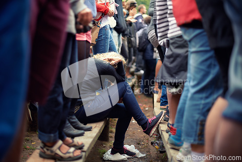 Image of Woman, sad and alone in crowd while sitting outside at festival, protest or concert in Poland. Female supporter, exhausted or overwhelmed during outdoor fundraising event during spring or autumn