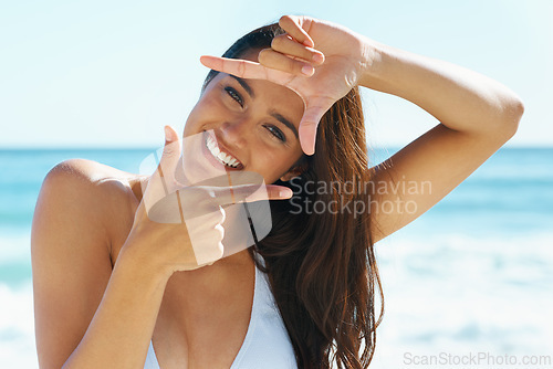 Image of Woman, sea and portrait with finger frame for smile, sign or emoji for photography with bikini in summer. Girl, person and happy at beach, sunshine and hands by face for symbol on holiday in Naples