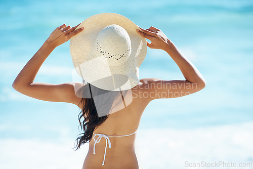 Image of Woman, hat and travel to beach or sea, nature and relaxing by ocean for peace on vacation. Female person, outdoors and calming waves on summer holiday, back and getaway to tropical island or water