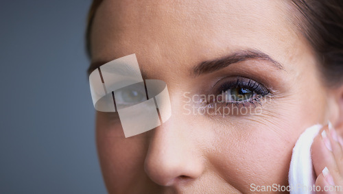 Image of Woman, eyes and pad for makeup, beauty or removal in anti aging or cosmetics on a gray studio background. Closeup of female person wiping face with cotton in satisfaction for collagen or cleaning
