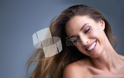 Image of Hair, beauty and happy woman in studio with cosmetics, shampoo or treatment results on grey background. Haircare, smile and model with growth, shine or texture satisfaction or clean scalp confidence