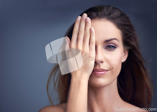 Image of Makeup, smile and hand on face of woman in studio for beauty, comparison or makeover on grey background. Half, portrait and female model with glowing skin, wellness or glamour treatment results