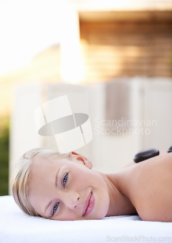 Image of Spa, woman and hot stone on massage bed with portrait for wellness, mockup and beauty treatment for body care. Person, face and stress relief at resort, salon table and relax on holiday or vacation