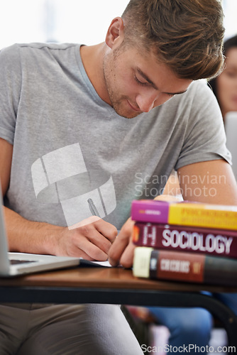 Image of Student at a desk, man and writing with textbooks, education and knowledge with exams and test. Person, college and guy with ideas and laptop with inspiration and studying with learning or university