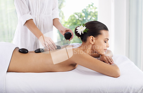 Image of Hot stone, woman and hands massage spine for skincare, beauty and pamper body for wellness at luxury salon. Therapist, rocks and back of person at spa for treatment, relax or health with masseuse