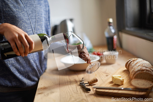 Image of Hands, pouring red wine and home for dinner, relax for peace and person with drink in kitchen. Alcohol, glass and bottle with refreshment, hydration with beverage and read to chill in apartment