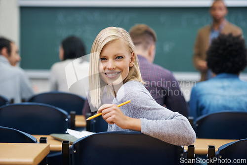 Image of University student, portrait and smile at classroom desk in London for english lecture, education or scholarship. Female person, face and pen at academy with professor for teaching, lesson or exam