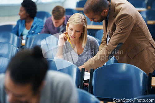 Image of University, helping and professor with student in classroom studying for test, exam or assignment. Education, learning and teacher talking and explaining college information to woman in lecture hall.