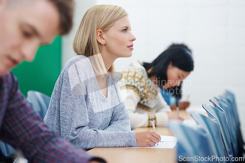 Image of University student, desk and test in classroom or thinking as assessment answer, education or knowledge. Female person, table and document at campus academy in London or exam, reading or scholarship