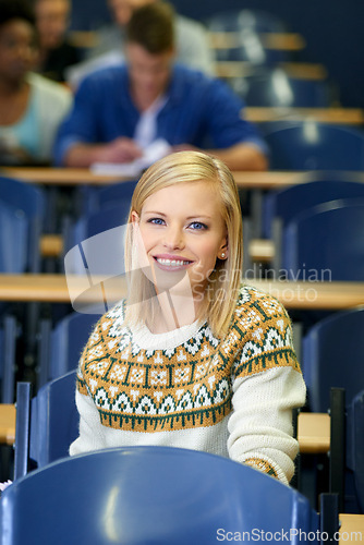 Image of University student, portrait and smile at desk in lecture hall in London for english class. education or scholarship. Female person, face and academy for teaching or learning course, lesson or exam