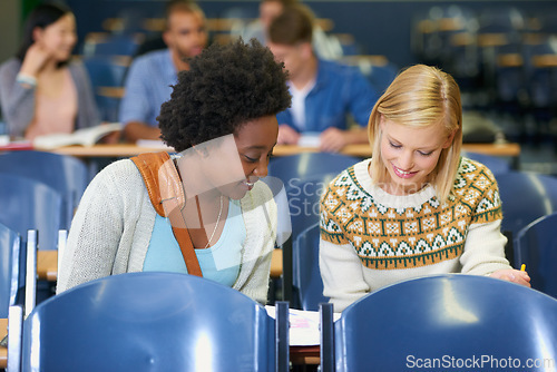 Image of Conversation, university and women students in classroom with textbooks and documents for information. Smile, discussion and female friends talking and studying for college test, exam or assignment.