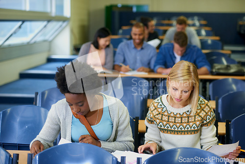 Image of Studying, university and women students in classroom with textbooks and documents for information. Bonding, discussion and female friends talking and learning for college test, exam or assignment.