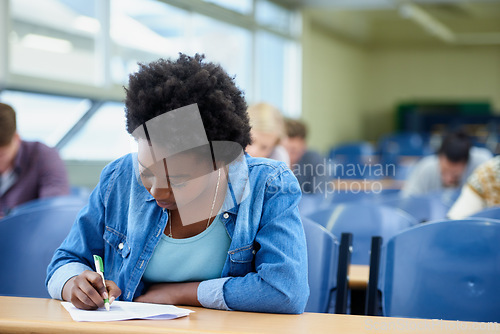 Image of Writing, university and black woman student in classroom studying for test, exam or assignment. Education, college and female person working on project with knowledge in lecture hall for learning.