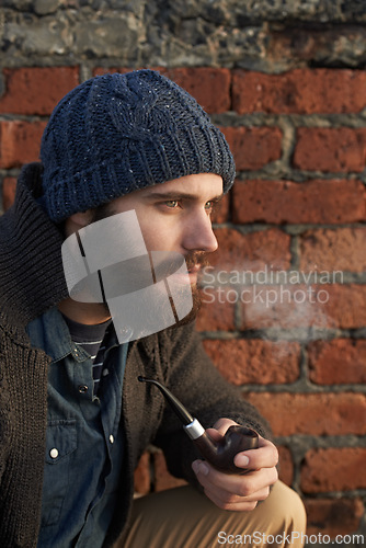 Image of Face, winter and pipe smoke with man outdoor on wall background for fashion, style or clothing. Morning, tobacco or habit and young person with beanie smoking in cold weather season to relax