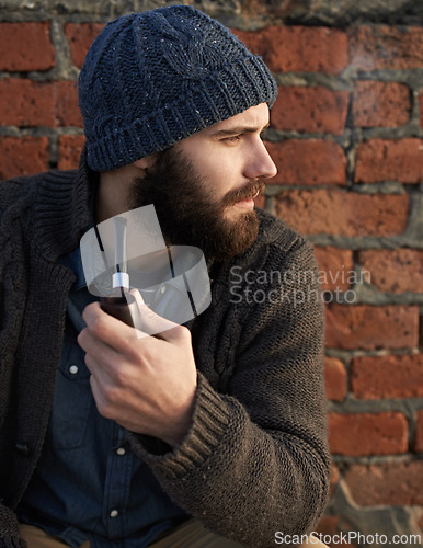Image of Man, pipe and thinking by brick wall for planning, ideas or smoking in winter with beanie on head. Male person, fashion and tobacco for style, vision or contemplating outdoors on cold morning