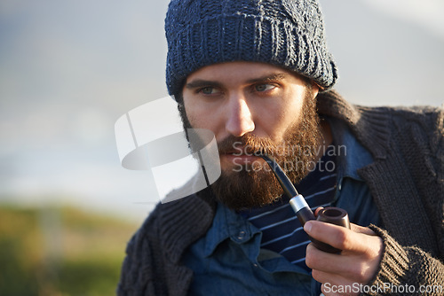 Image of Holiday, man and smoker with pipe in nature, lighter and tobacco habit on winter morning for sunrise. English guy, nicotine or vintage smoking for calm, satisfaction or vacation by ocean in cape town