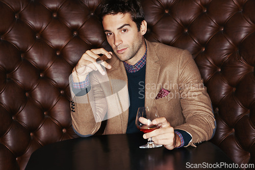 Image of Portrait, cigar and businessman drinking at club, fashion and person in a suit with alcohol at vintage bar. Face, smoking and serious person with whiskey, scotch and brandy in glass for luxury at pub