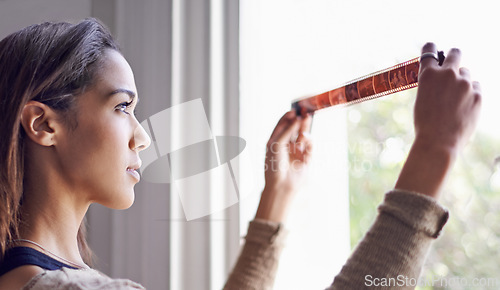 Image of Woman, photographer and filmstrip negative for creative prints at window for retro images for portfolio, inspiration or hobby. Female person, artistic and roll for picture, development or photoshoot