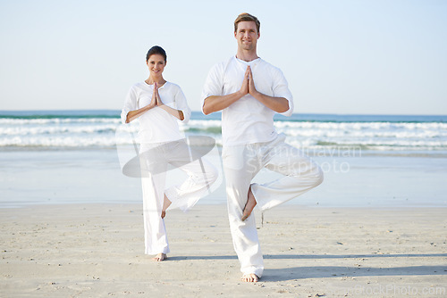 Image of Balance, yoga and couple on beach in morning for fitness, exercise and workout in standing pose. Nature, pilates and man and woman by ocean for meditation, wellness and healthy body outdoors together