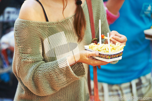 Image of Hands, person and eating french fries outdoor, delicious snack and tasty cuisine for nutrition in summer. Fast food, chips and hungry for unhealthy lunch, junk and fresh crispy potato meal for diet