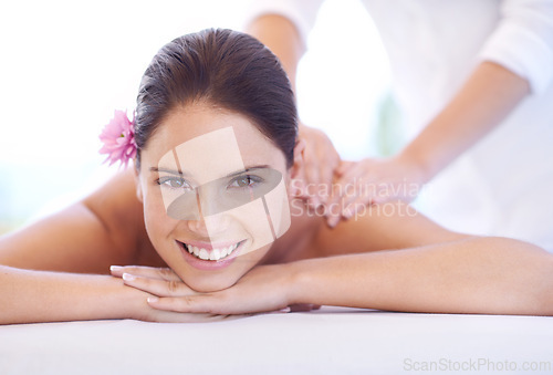 Image of Relax, massage and portrait of woman at hotel with flower for health, wellness or luxury holistic treatment. Self care, peace and girl on bed with masseuse for body therapy, smile or calm spa service