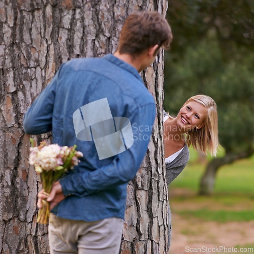 Image of Couple, park and love for valentines day with flower in romance, boyfriend for girlfriend. Romantic, outdoor and date to play with hide and seek for bonding, happiness and relax for wellness