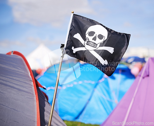 Image of Pirate flag, tent and camping at festival outdoor in summer for party, event or celebration closeup. Skull, crossbones or jolly roger in nature for performance, entertainment or adventure with crowd