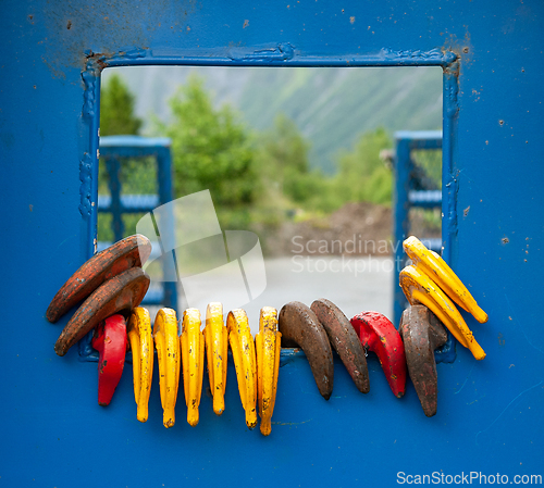 Image of Colorful hooks hanging on a blue metal frame outdoors