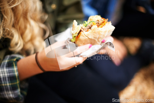 Image of Woman, hands and burger with hungry for food, nutrition and take away on holiday in outdoor. Person, eating and satisfaction with protein roll in hand, closeup or foodie outside on vacation leisure